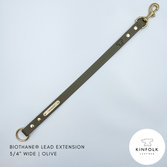 Olive green leather lead extension with gold hardware on a light gray background, featuring the Kinfolk Leather logo.