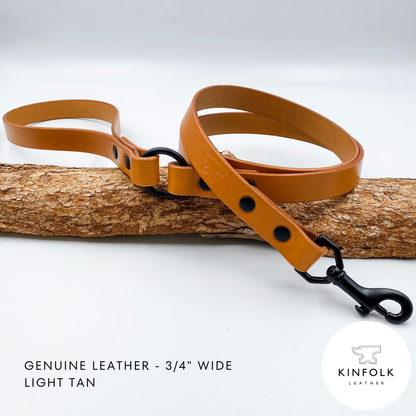 Light tan leather dog leash with black hardware on a wooden log against a white background, featuring the Kinfolk Leather logo.