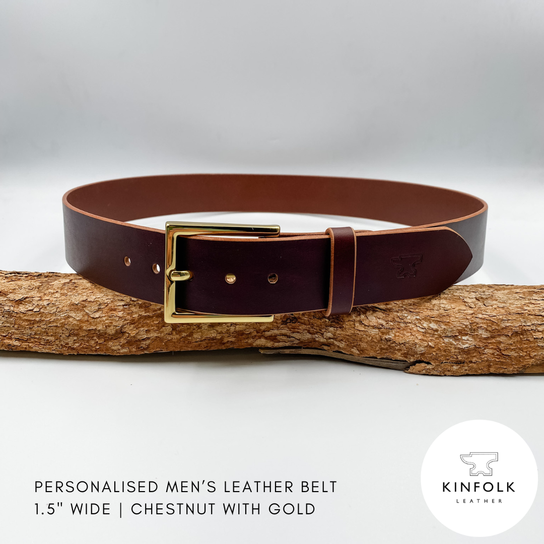 Brown leather belt with gold buckle on a wooden log against a white background, featuring the Kinfolk Leather logo.