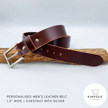 Brown leather belt with silver buckle on a wooden block against a white background, featuring the Kinfolk Leather logo.